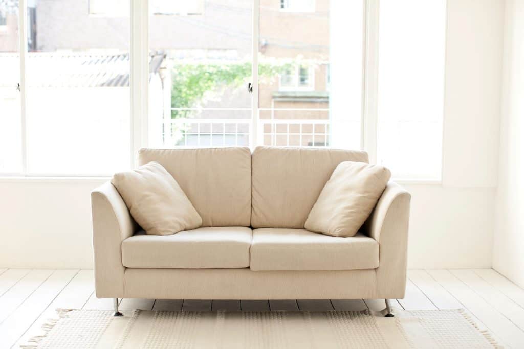 A cozy cream colored loveseat inside a white living room