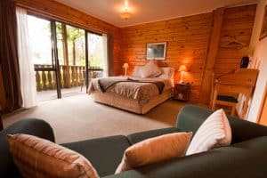 Lodge themed bedroom with wooden paneling walls, carpet flooring and a cozy bed, How To Decorate Wood Paneling Without Painting