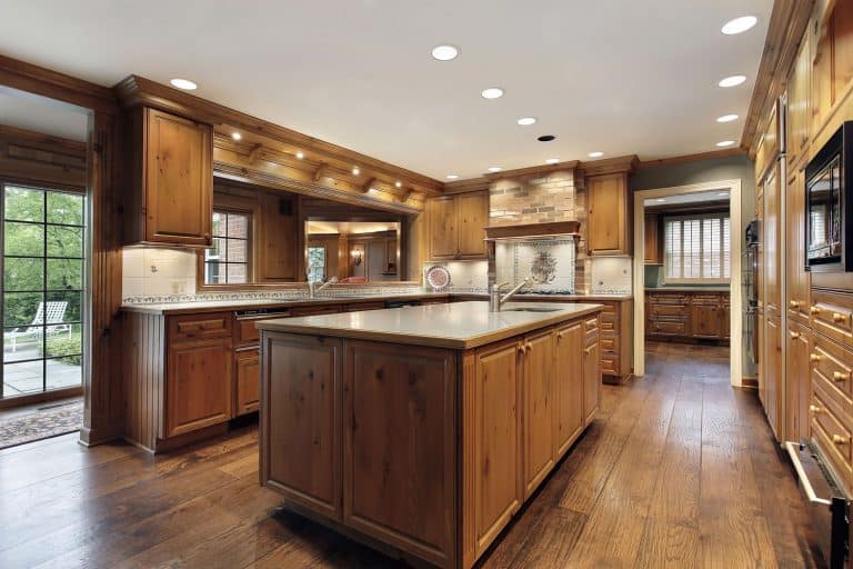 A craftsman inspired kitchen area with wooden cabinetry, wooden flooring, and granite countertops