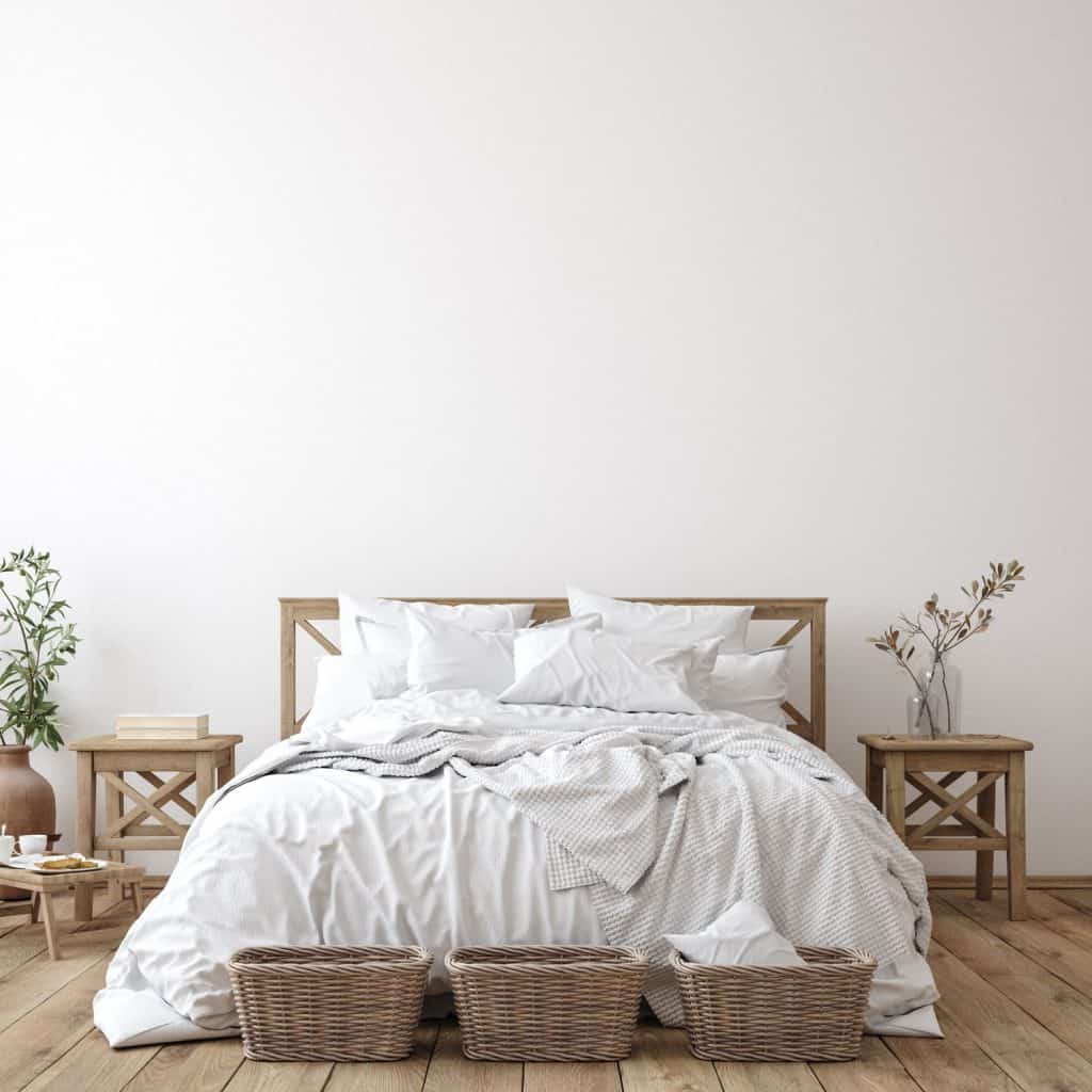 A farmhouse themed bedroom with white beddings and a wooden nightstand on the sides