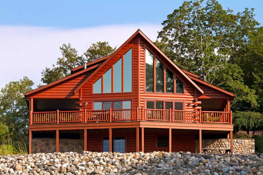Gorgeous log cabin with a modern mix of huge windows and masonry stone walls and landscaping, How Much Does Log Siding Cost (Inc. Faux Log Siding)