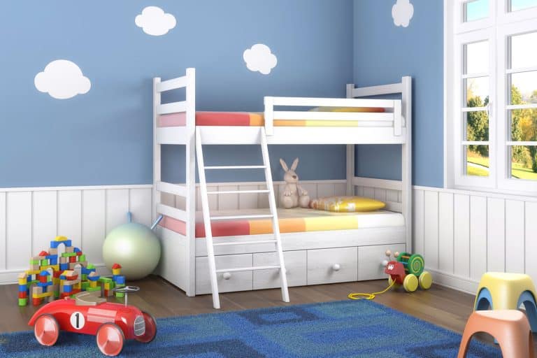 Kids room with blue walls decorated with clouds and a blue carpet on the middle of the room