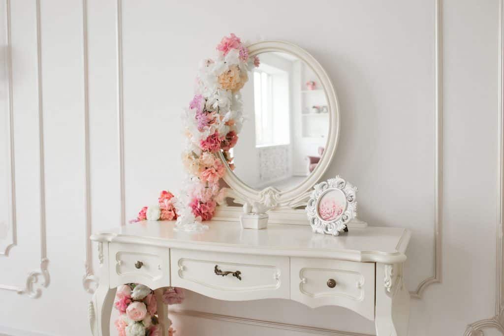 A ladies bedroom with a white vintage styled boudoir table with a mirror on top