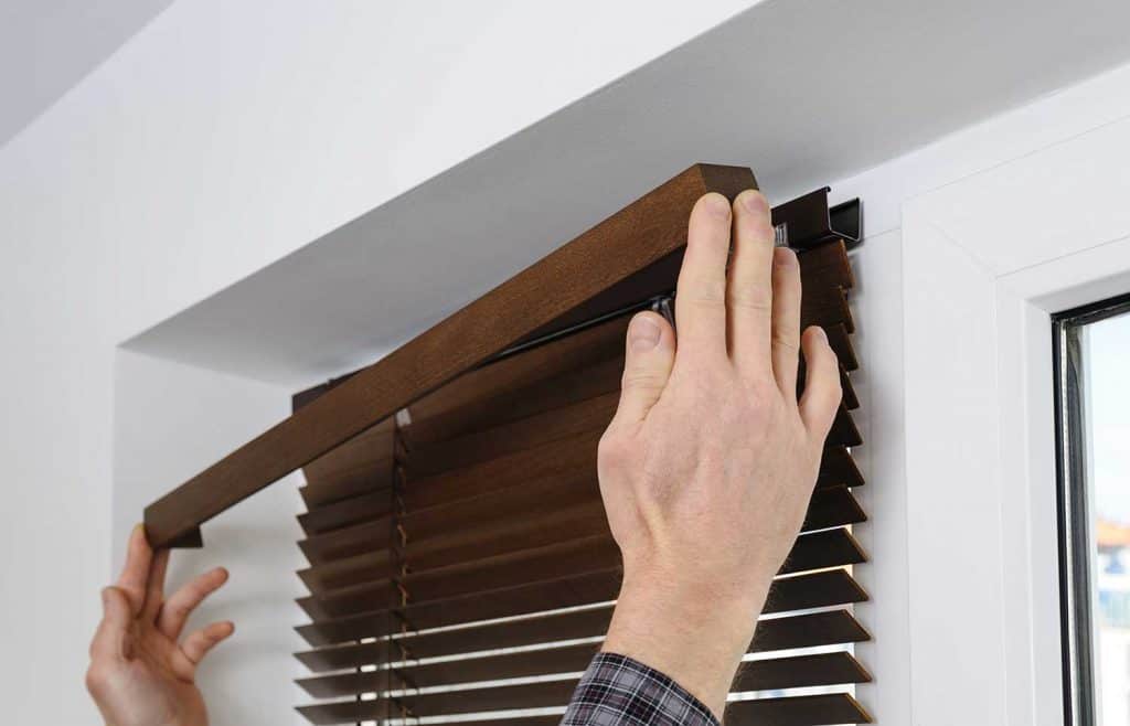 A man installing wooden blinds