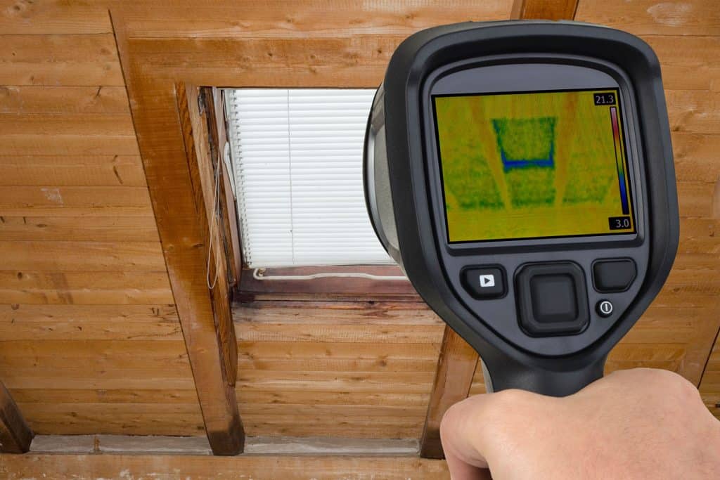 A man using a thermal scanner to show the heat spots of the attic