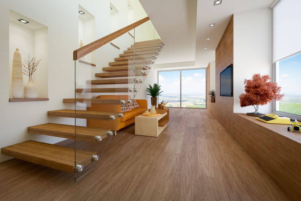 A modern contemporary house with wooden laminated flooring and a staircase with a glass wall stair railing