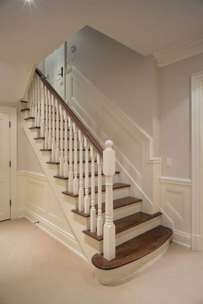 An old fashioned staircase with wooden flooring and white painted banister