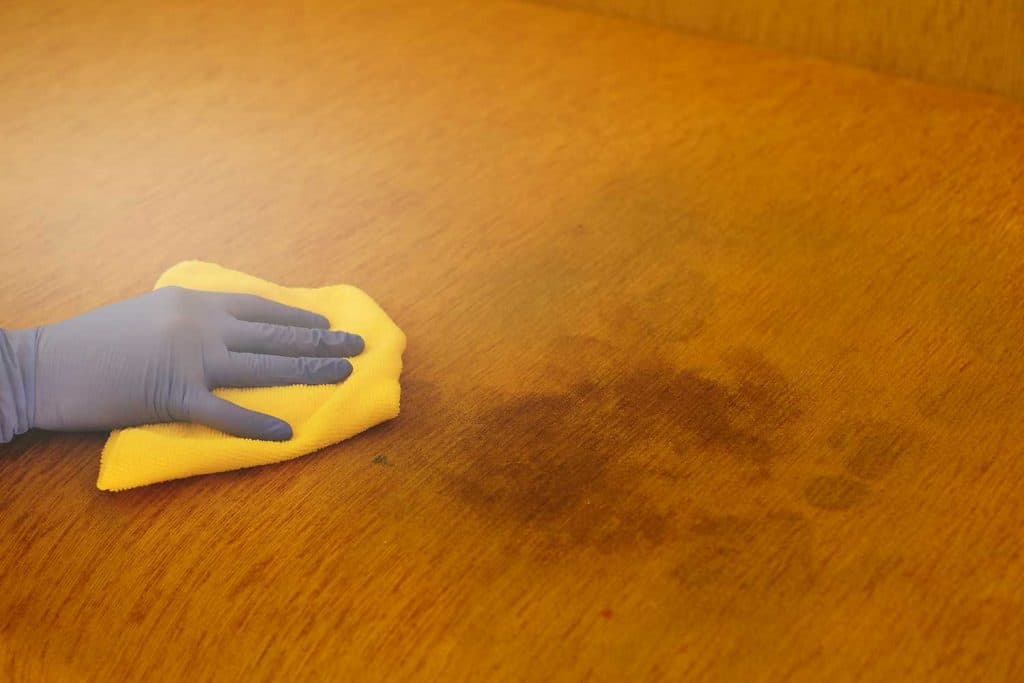A person cleaning dirty stains on the sofa with yellow fabric