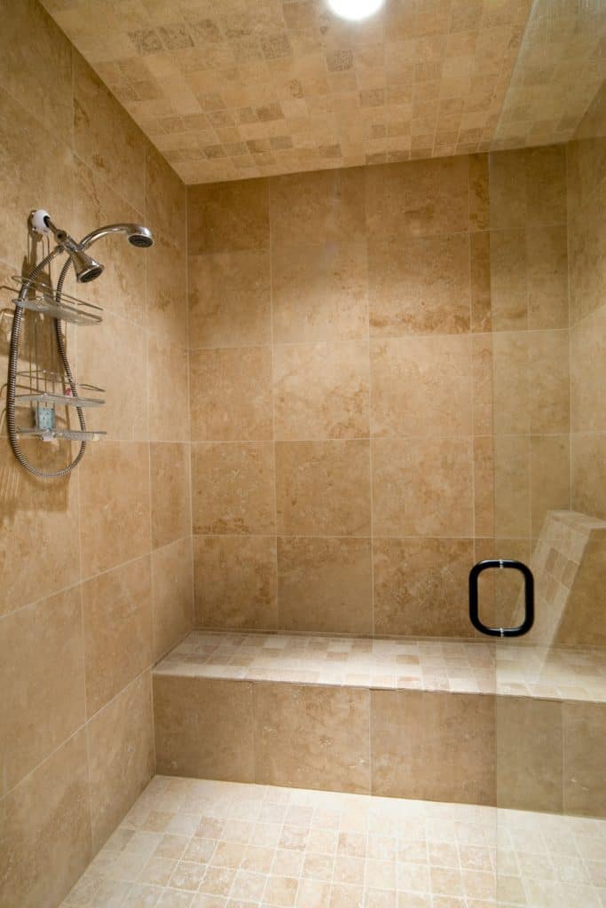 A stone tiled bathroom with a glass walled shower area