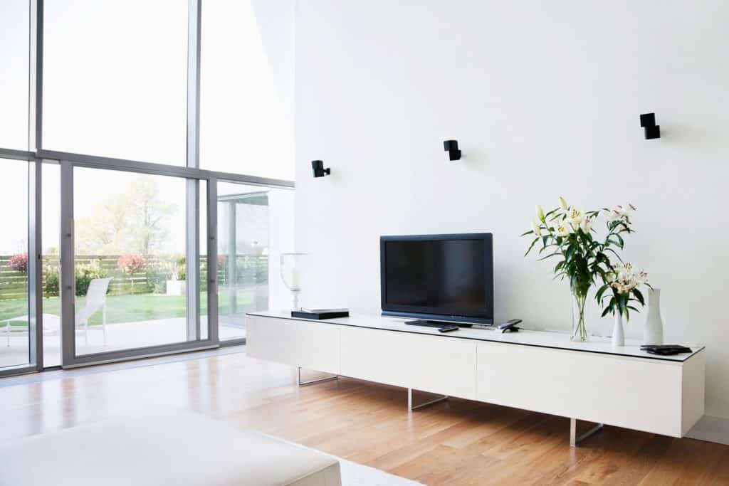 A white TV wall unit with a flat screen TV on it inside a luxurious modern contemporary living room 