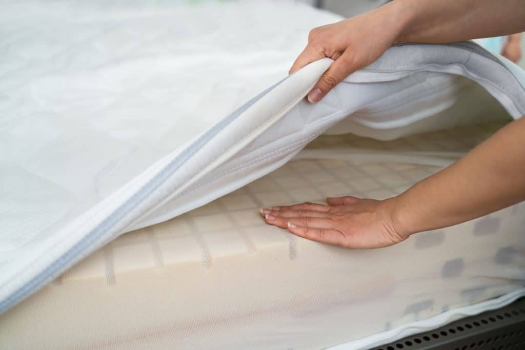 A woman properly placing her mattress topper on her bed