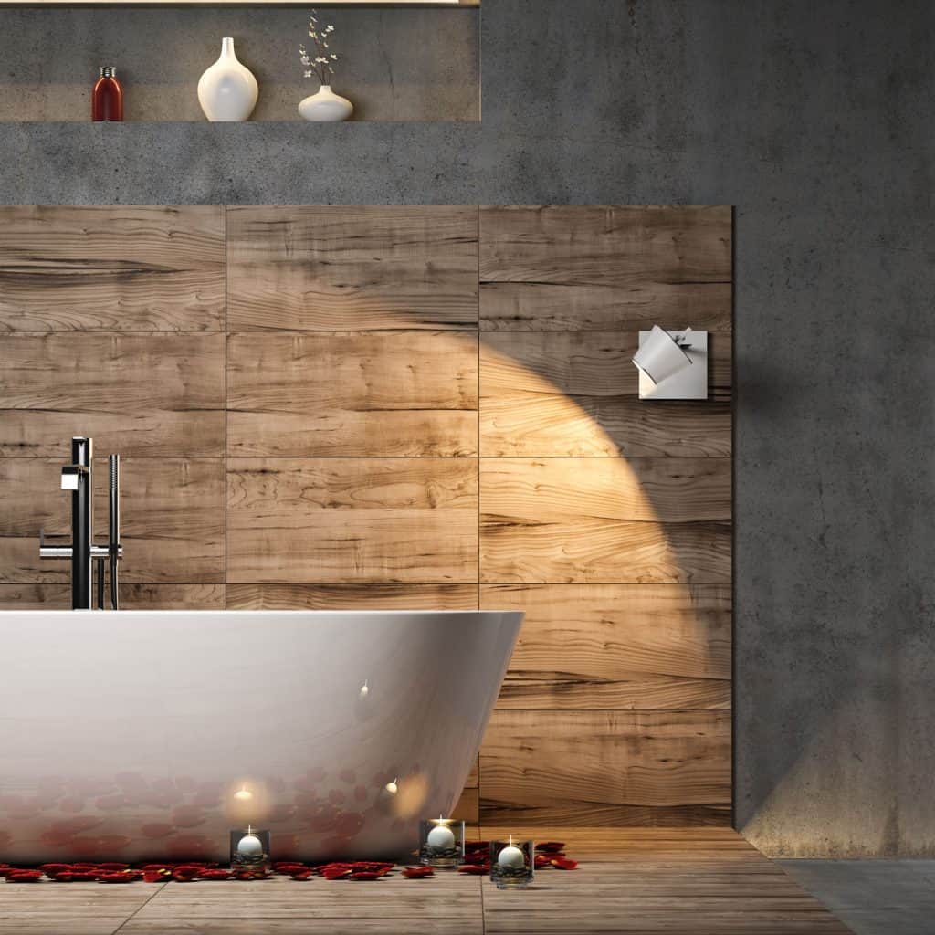 A wooden paneled decorative bathroom section with a white bathtub and scented candles on the floor