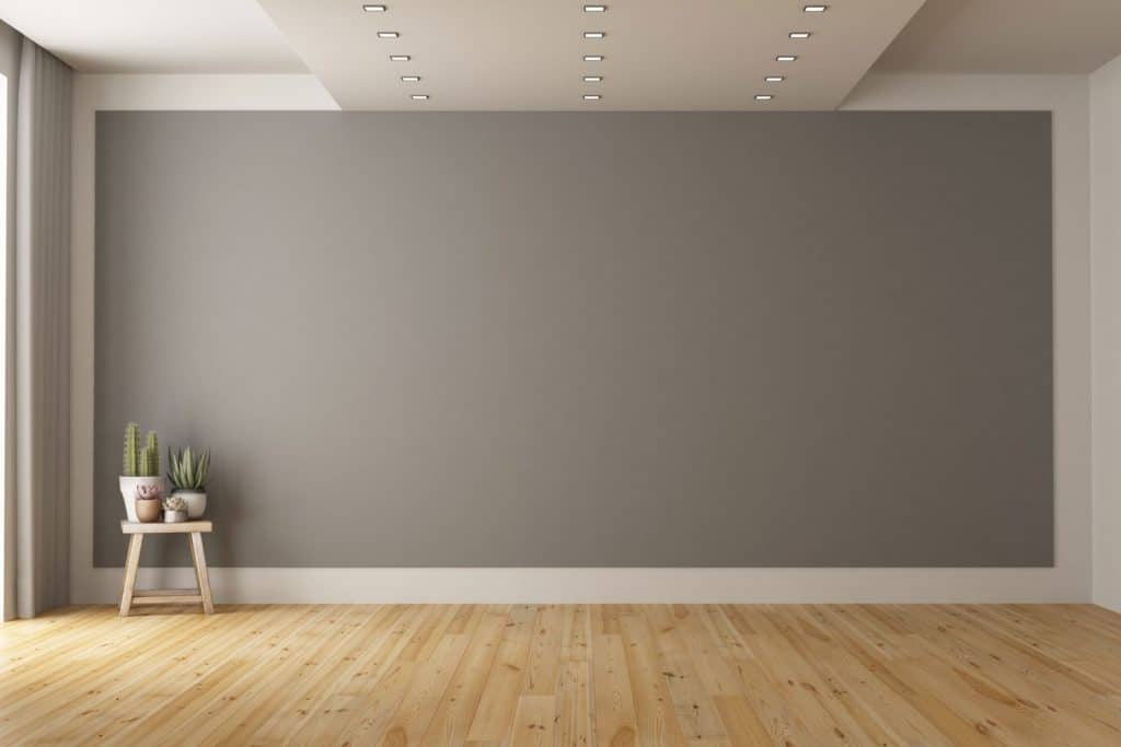 An empty living room with gray walls and a wooden paneled flooring