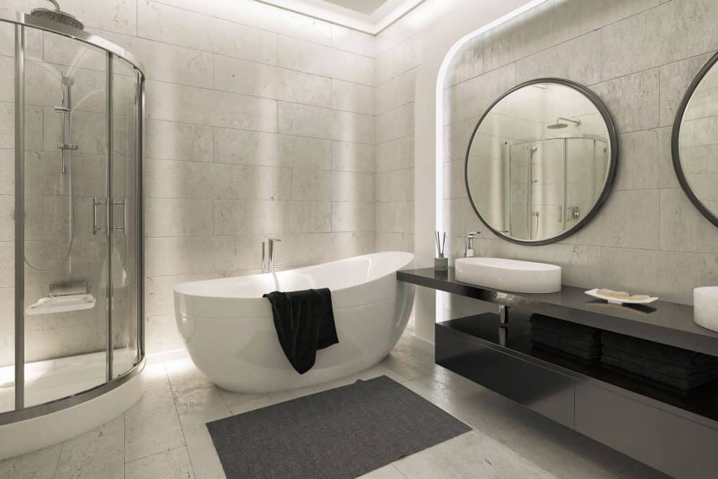 Bathroom with a double round mirror on the vanity area semi-circular shower area and a white bathtub, 25 Grey and White Bathrooms