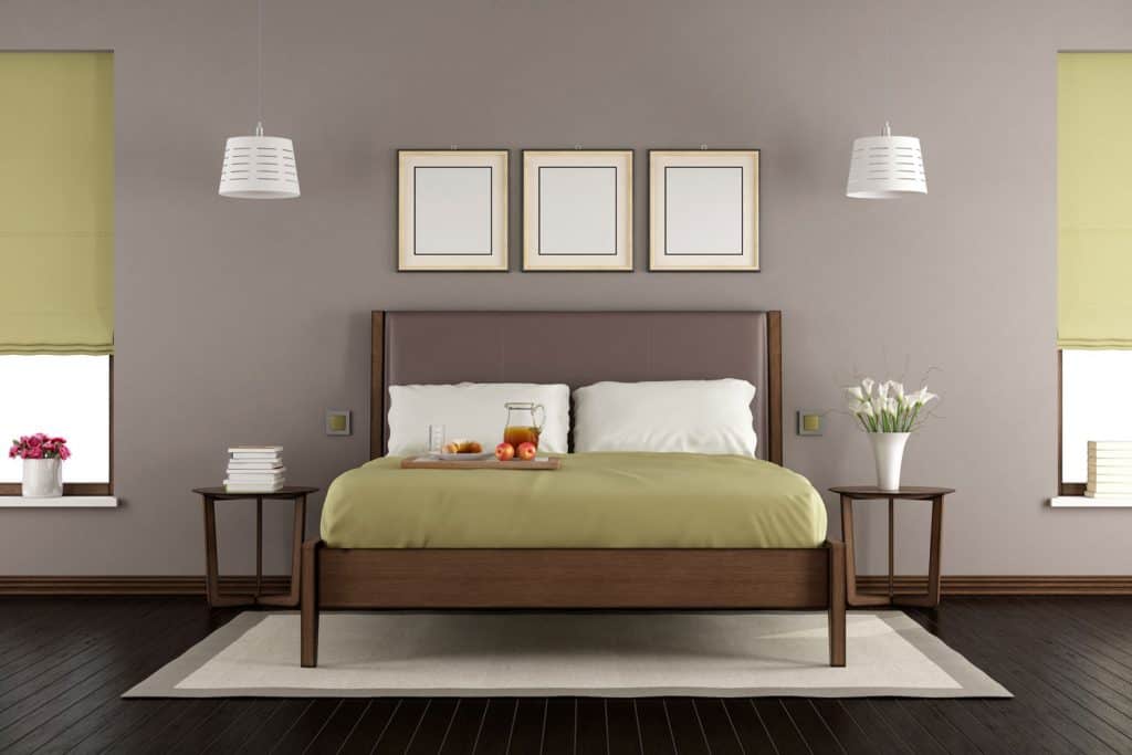 Brown bedroom with a brown bed with an off-green colored bedding and white pillows