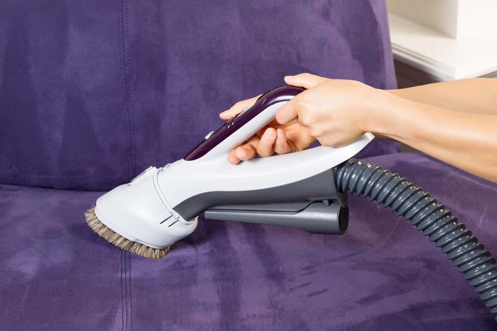 Cleaning leather sofa with vacuum brush
