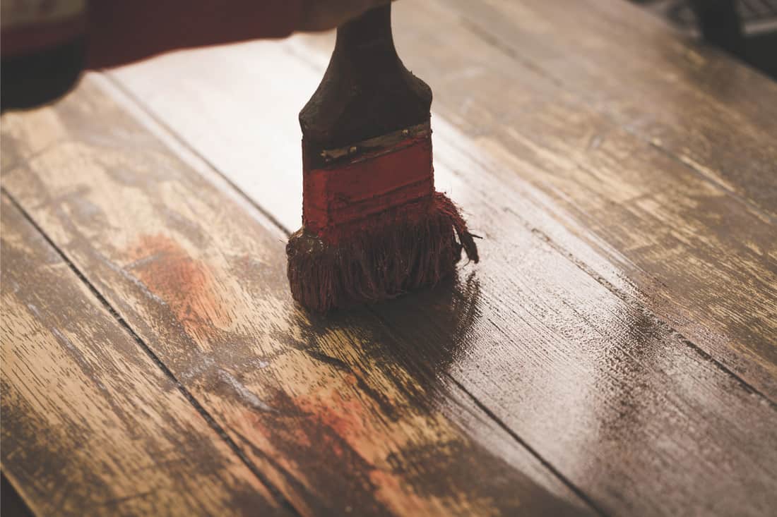 Main d'artisan peignant la couleur brune sur la table en bois