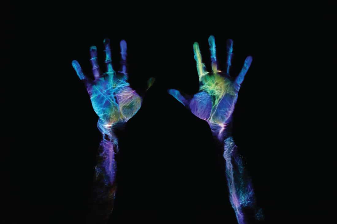 Fluorescent multicolored hand print on black background