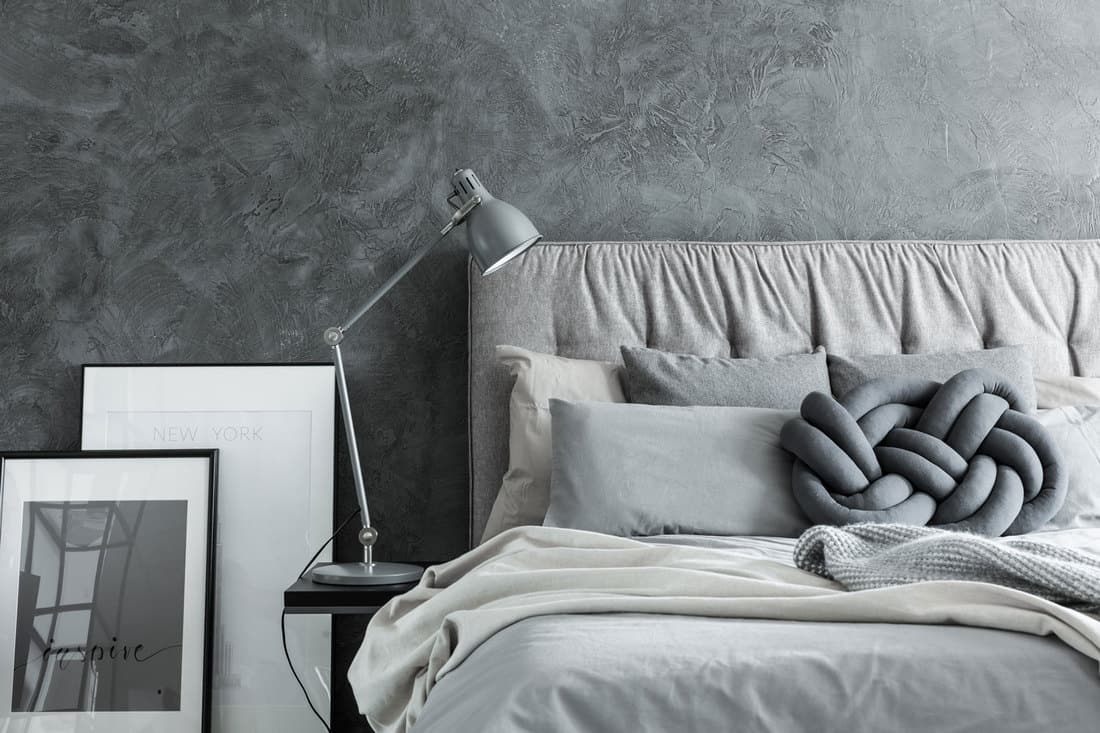 A gray and cream themed bedroom with light gray beddings and a study lamp on the side, What Color Bedding Goes With A Grey Headboard?