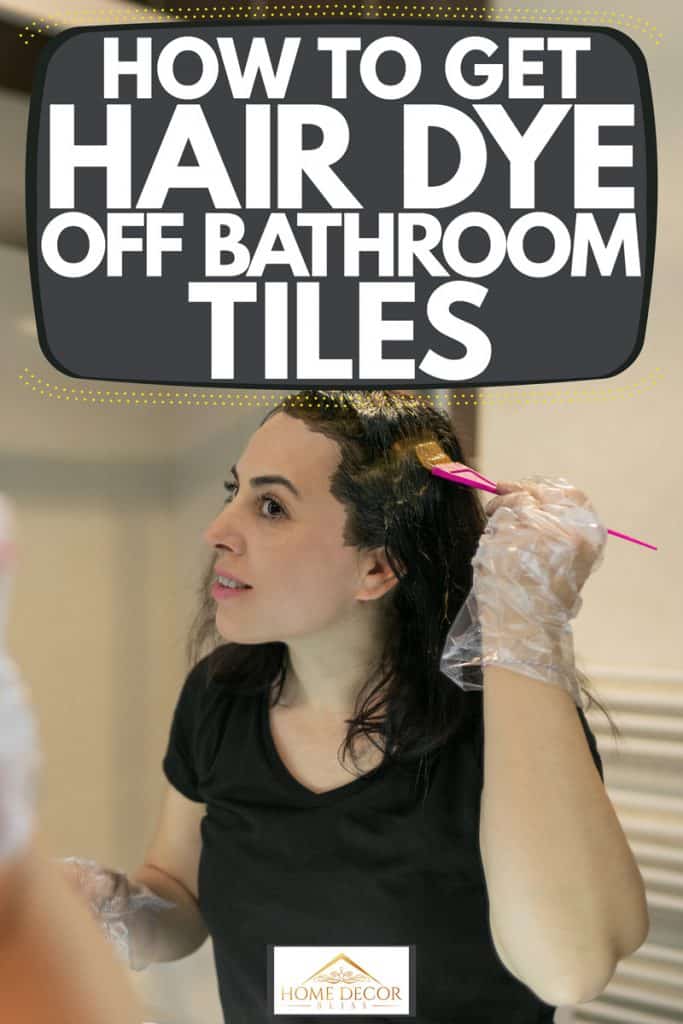 A woman looking on the mirror while putting on hair dye on the bathroom, How To Get Hair Dye Off Bathroom Tiles