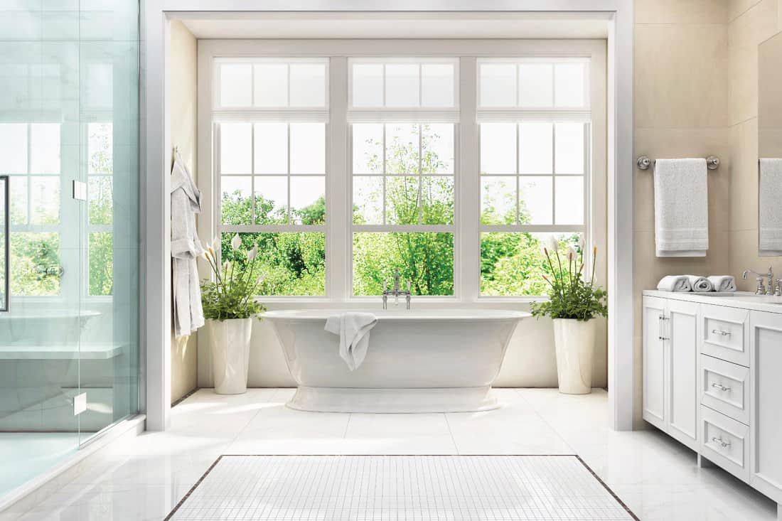 Large white bathroom with bath, large window, shower and two washbasins
