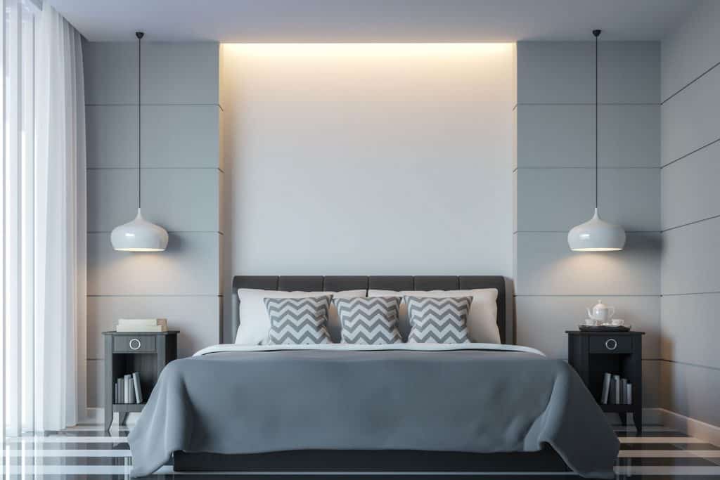 Luxurious modern themed bedroom with hanging lamps and gray beddings with a gray headboard