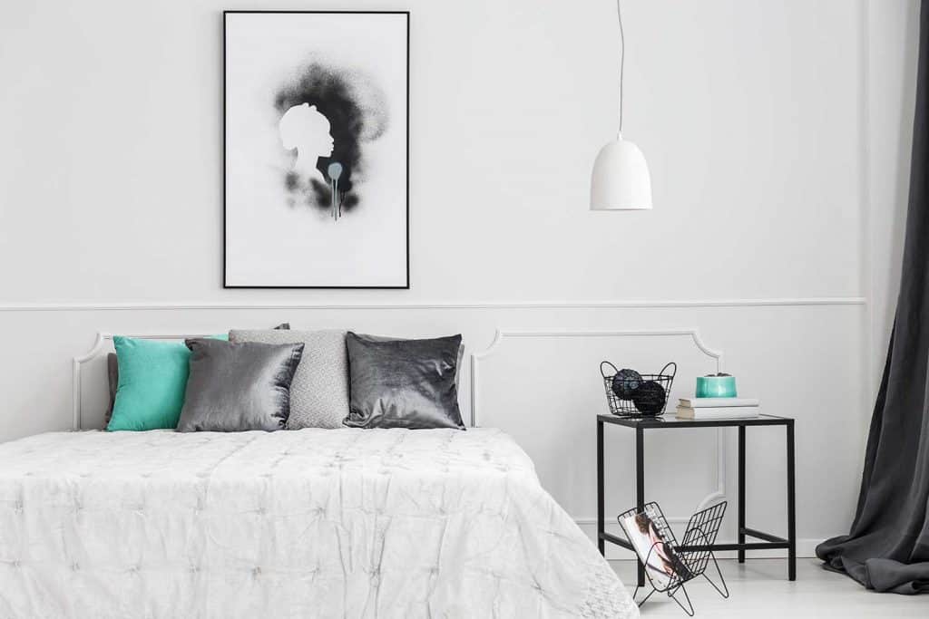 Minimalist, framed poster mock-up on a white wall of an artistic bedroom interior with elegant decor and gray textiles