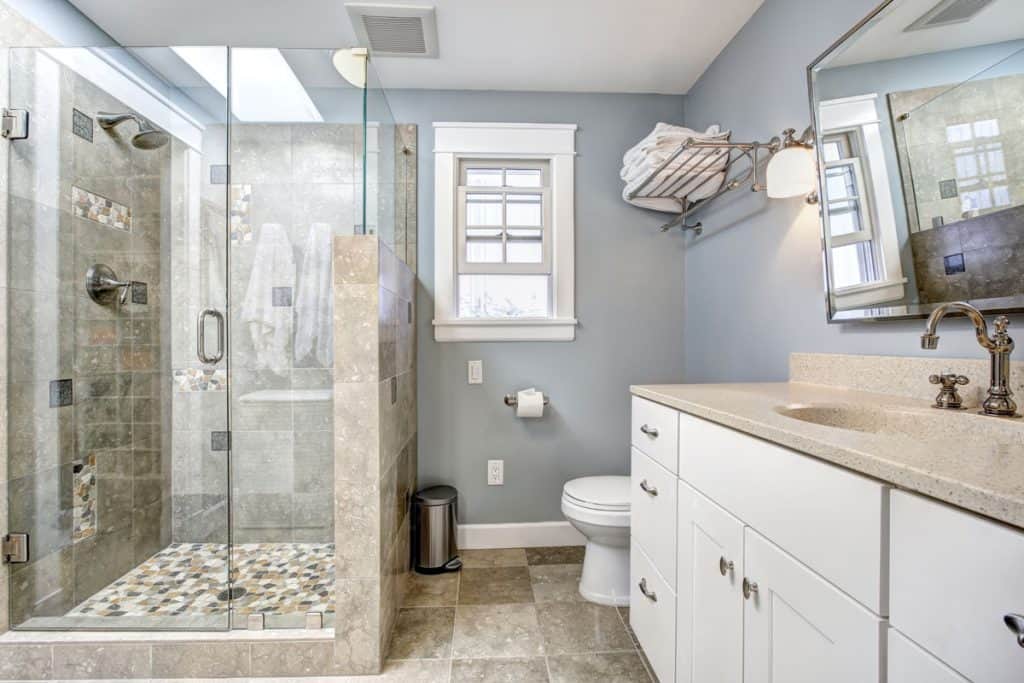 Modern bathroom with light blue walls, glass wall shower area and a class designed lavatory