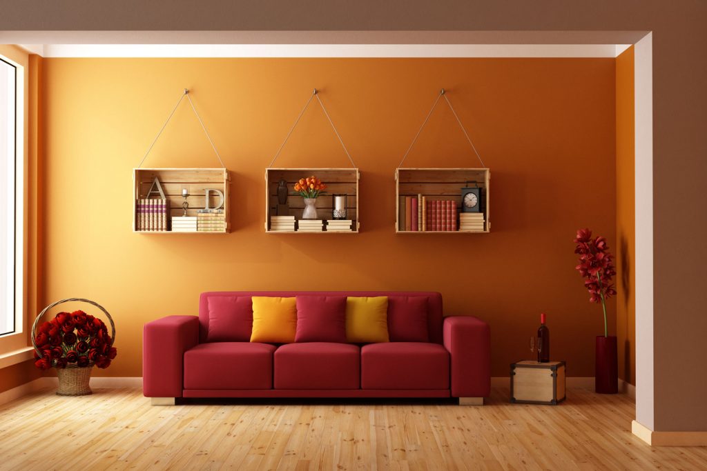 Modern classic themed living room with a red couch and three hanging cabinets hanged on an orange wall