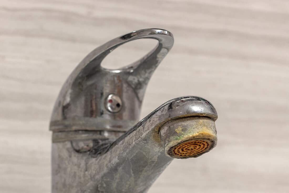 Old bathroom sink faucet contaminated with calcium, grime and rust