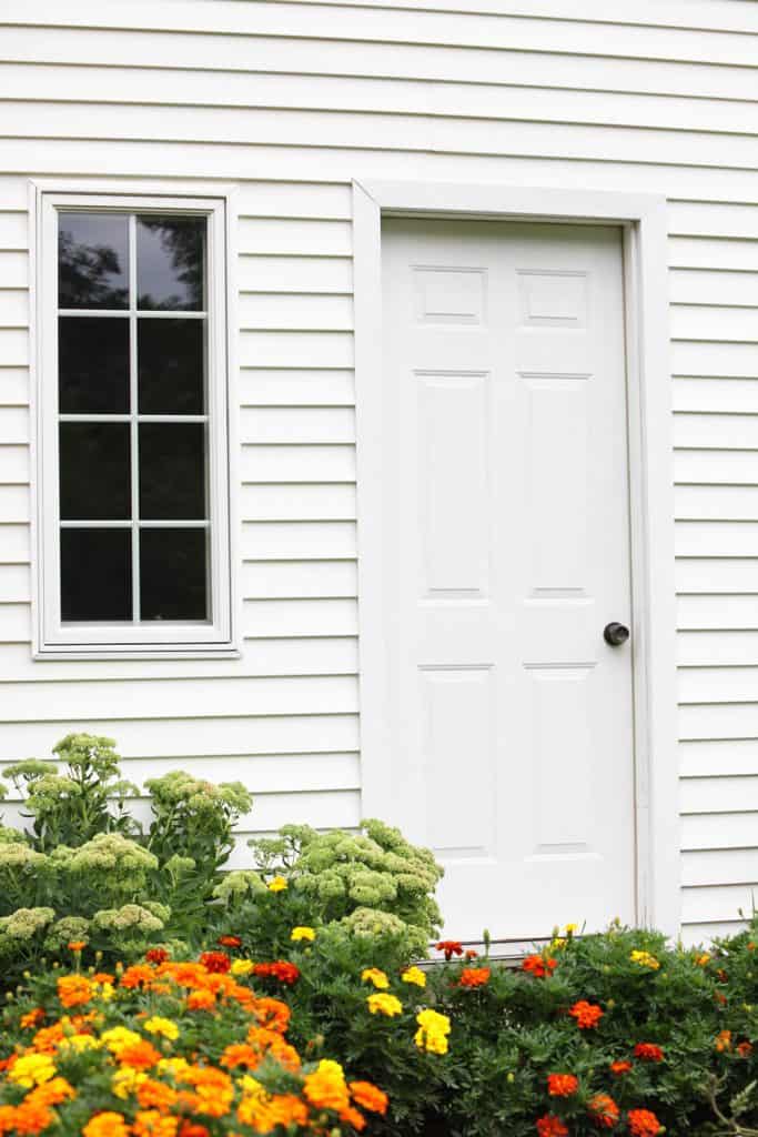 Porch with white wooden sidings with a white door and small front porch window