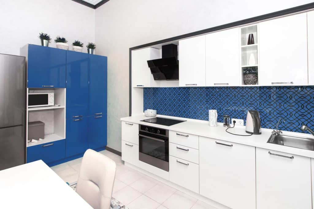 Pure white cabinets with blue blacksplash and white flooring