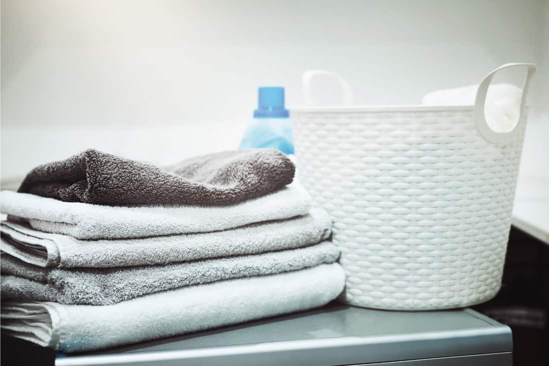Still life shot of linen, and towels, laundry basket on a washing machine, How To Soften Towels (Including Without A Dryer)