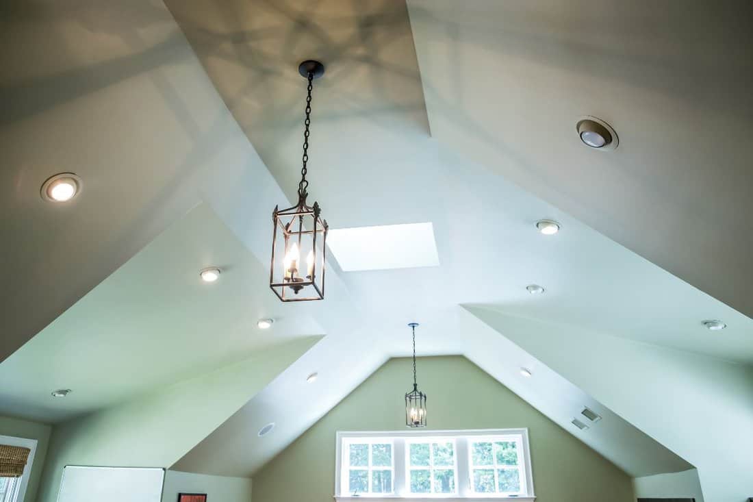 Vaulted ceiling with a modern Gothic mid evil iron metal hanging lights and a green walls.