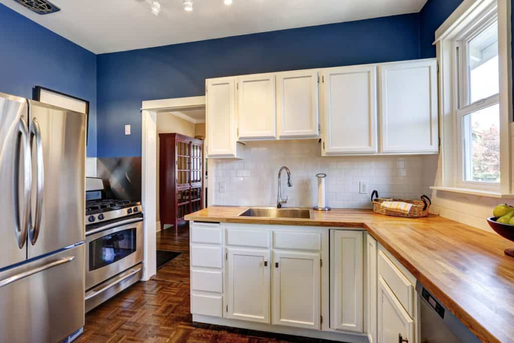 White cabinets inside a luxurious kitchen with blue painted walls