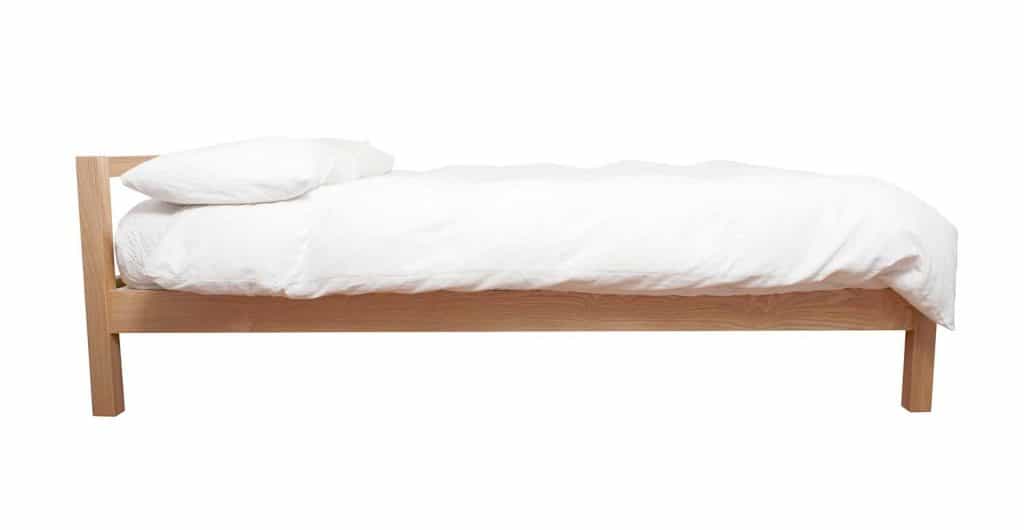 Wooden bed with white sheet and white pillow