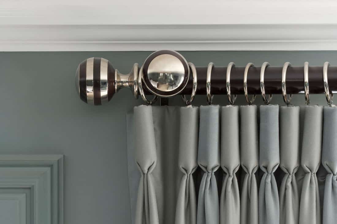 beautiful grey-green curtains hanging from a wood and metal curtain rail with metal rings and set against a green wall with white cornice, Standard Curtain Rod Lengths [Chart Included]