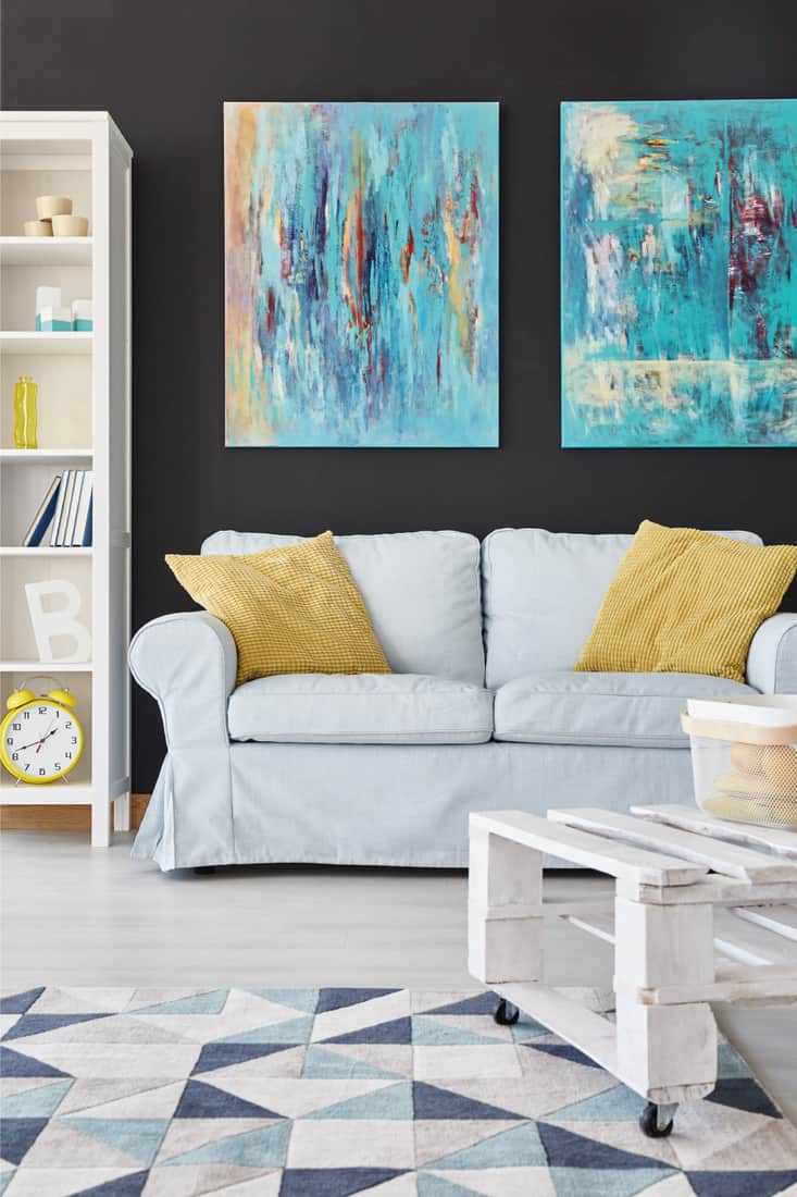 Tapis à motif de couleur sur un sol gris dans un salon avec canapé, table centrale et peinture au mur