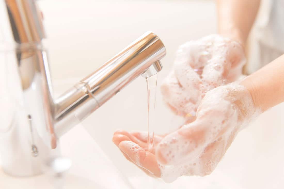 man washing hands with soap in bathroom sink