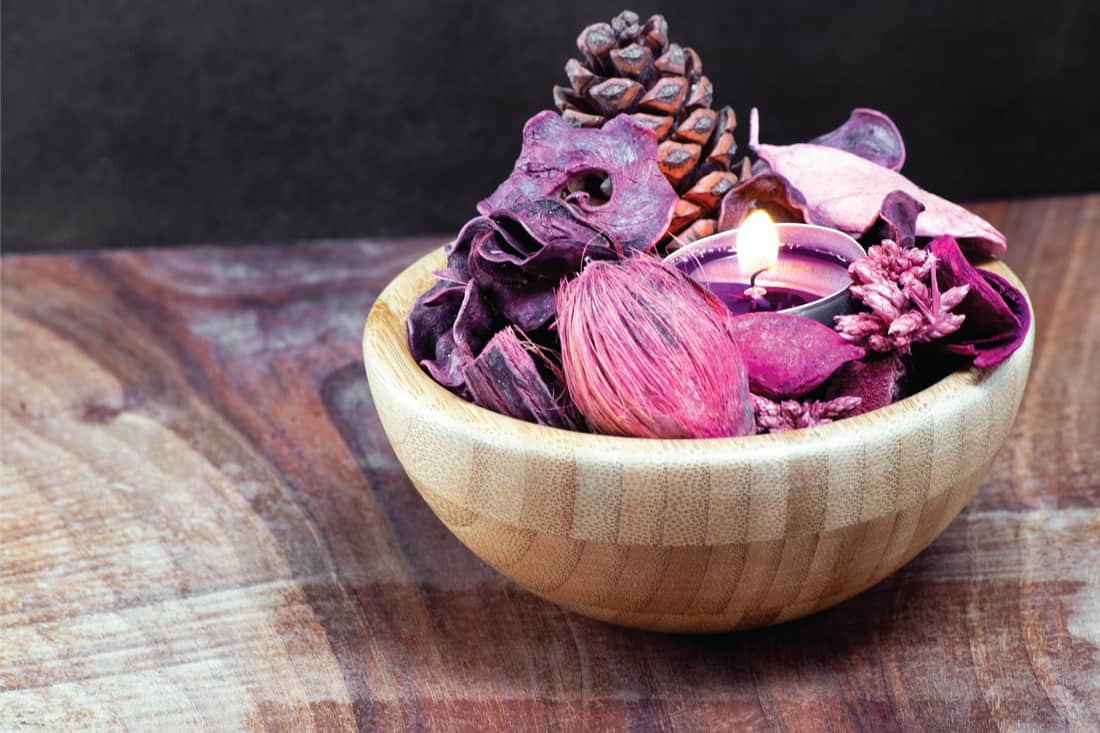 pourple tealight and dry potpourri in a wooden bowl over a table