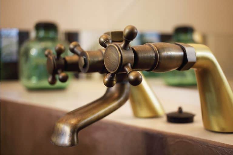 vintage bronze faucet placed in the bathroom of a luxury room in a country cottage hotel, How To Clean Bronze Faucets (And Other Bronze Bathroom Fixtures)