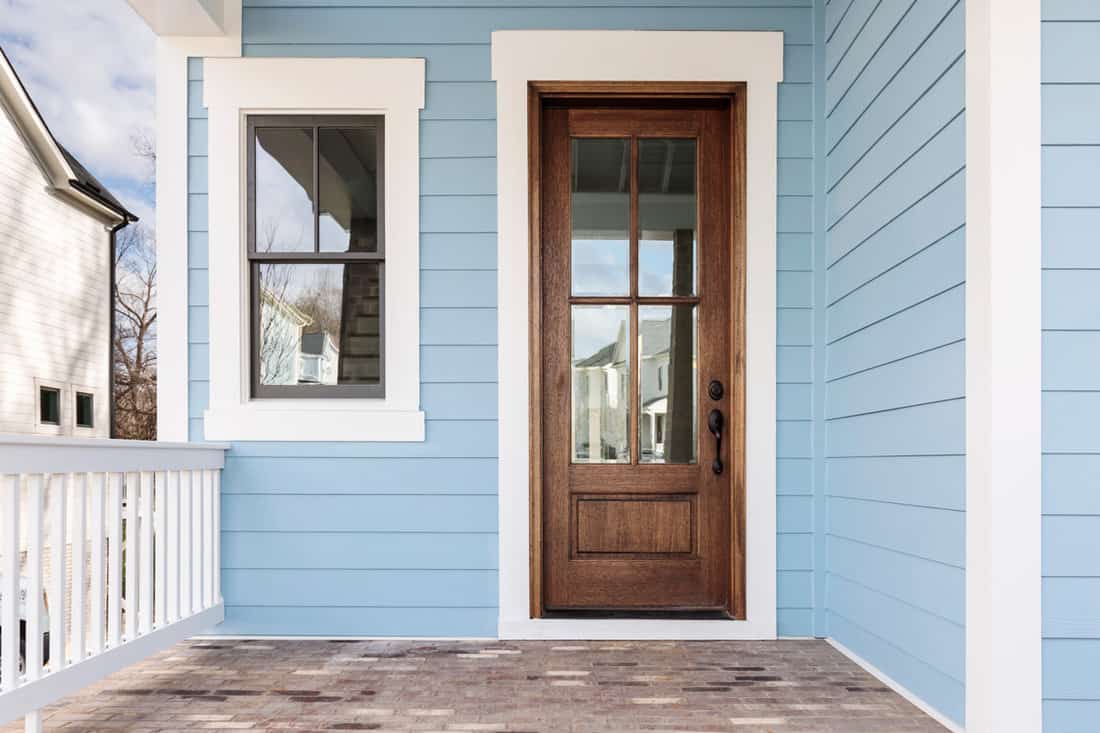 A blue walls porch with a brown door and brown window