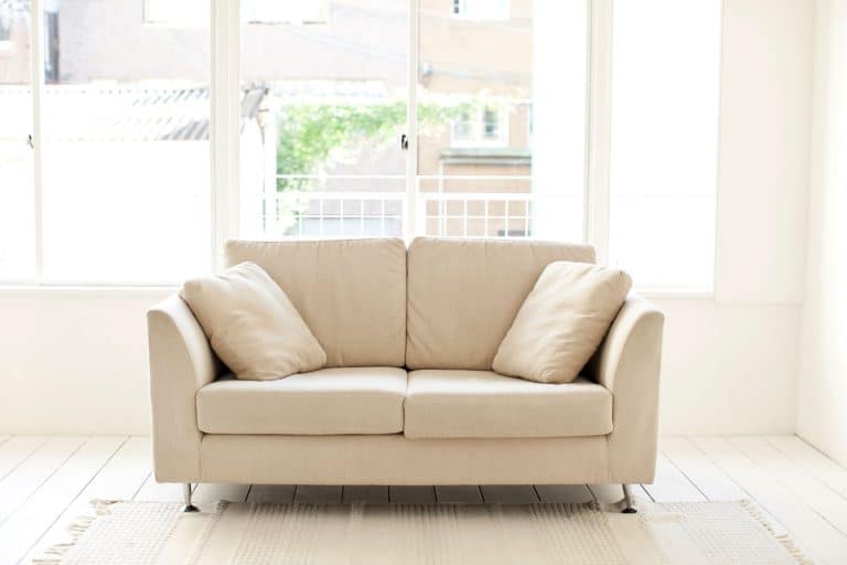 A cream colored loveseat inside a white living room, Can You Sleep On A Loveseat?