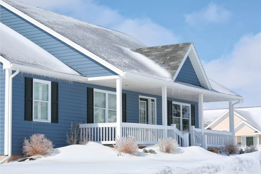 A family home in the suburbs on a sunny winter day with blue vinyl siding