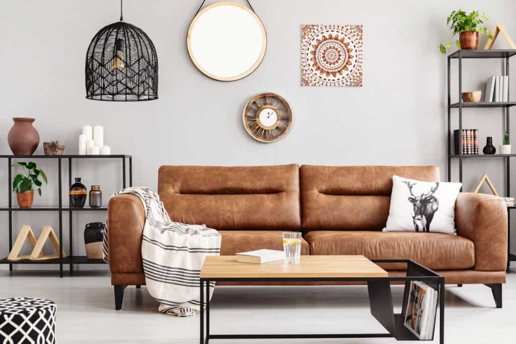 Un magnifique canapé en cuir dans un salon blanc d'inspiration rétro avec des armoires et des séparateurs de style ethno