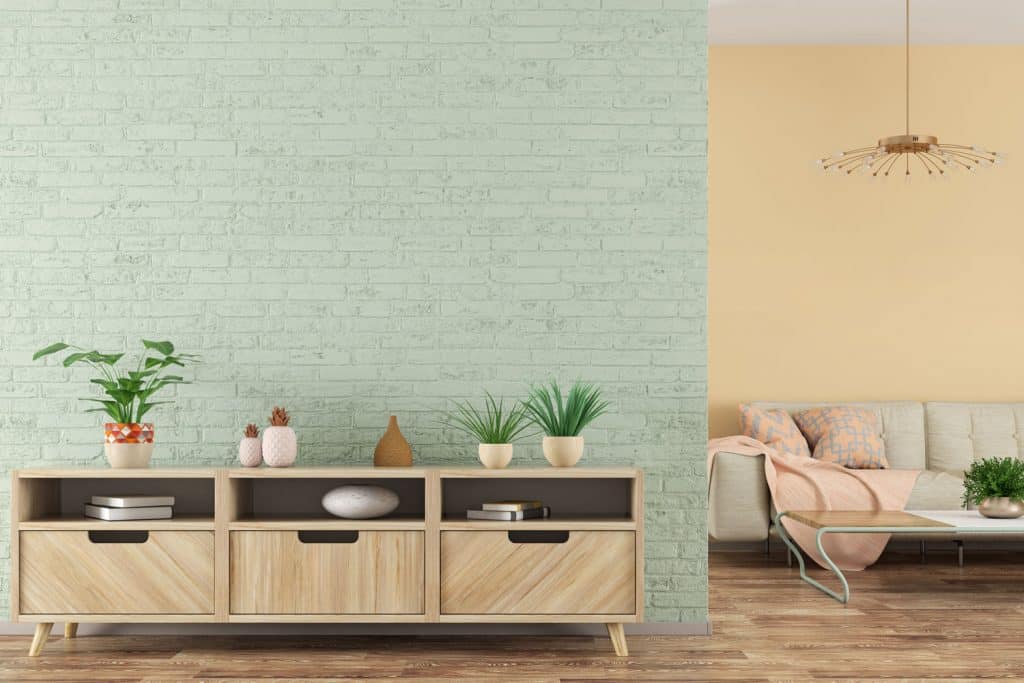 A light sky blue colored wall with a small wall unit cabinetry with indoor plants on top