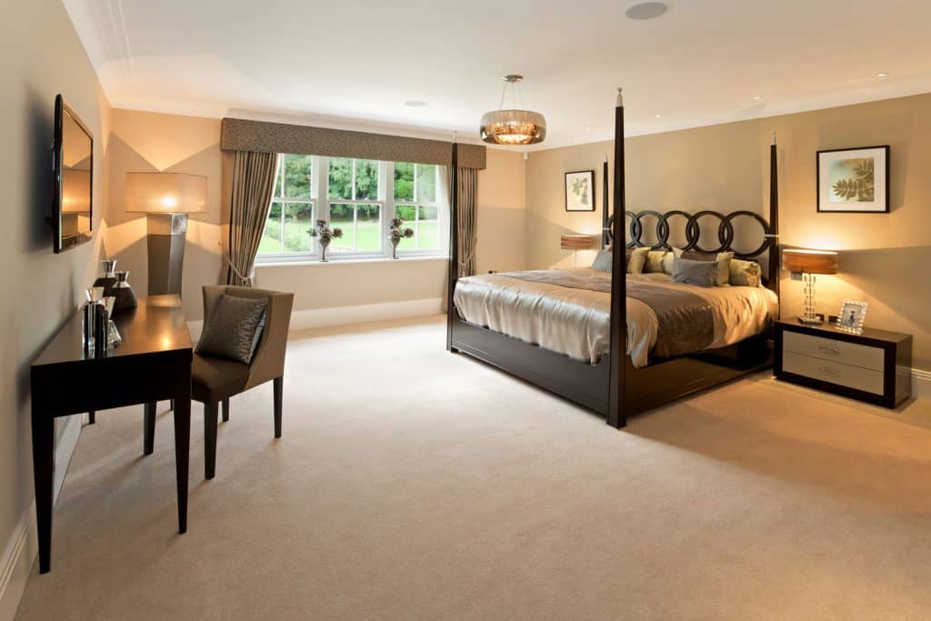 Une chambre luxueuse et spacieuse avec de la moquette beige assortie à des meubles de style rétro et un rideau vert en arrière-plan