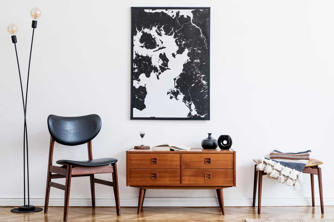 A minimalist concept living room with a small reading chair, wooden console table, and a mock up canvas with black and white painting, Where To Place A Console Table [7 Locations Explored]