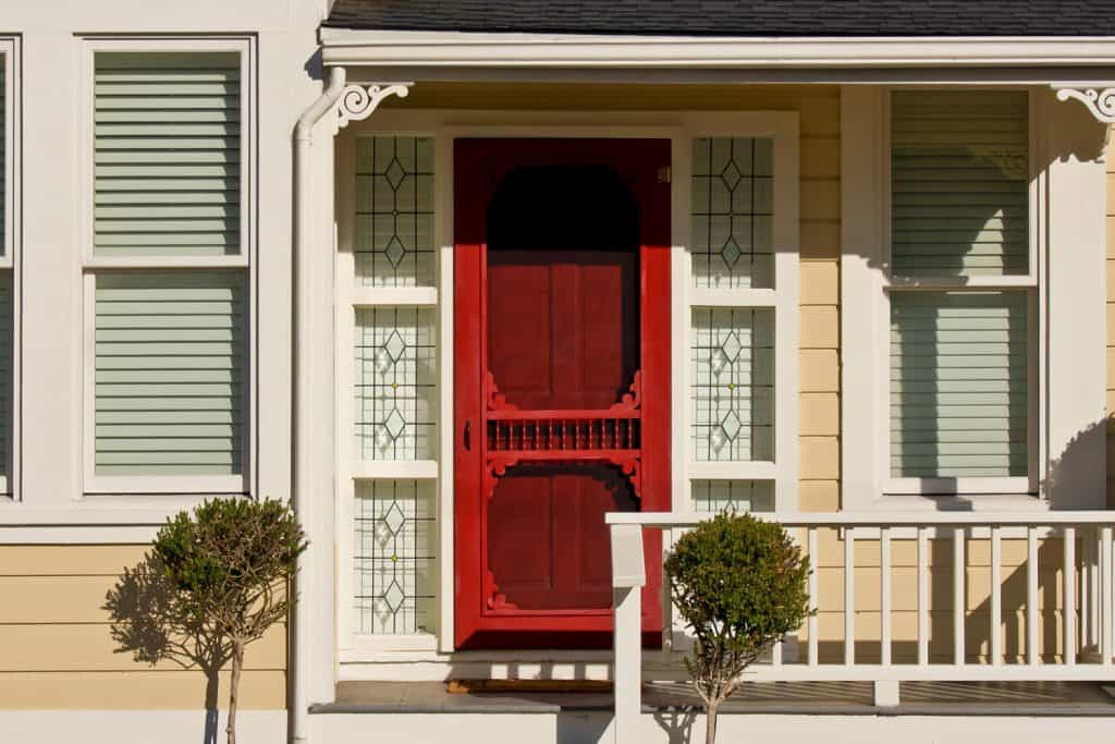 A Victorian inspired front porch with a red front door