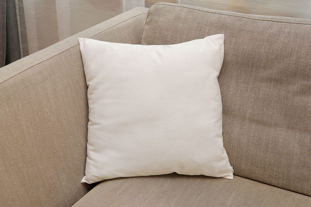 A white throw pillows or cushion left on the couch